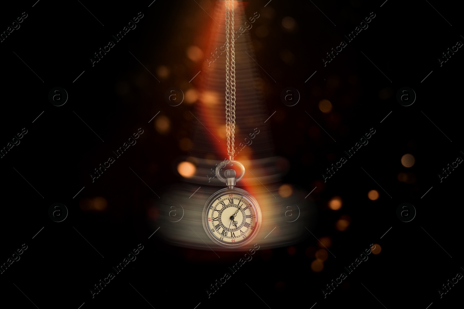 Image of Hypnosis session. Vintage pocket watch swinging on black background, motion blur effect. Magic lights