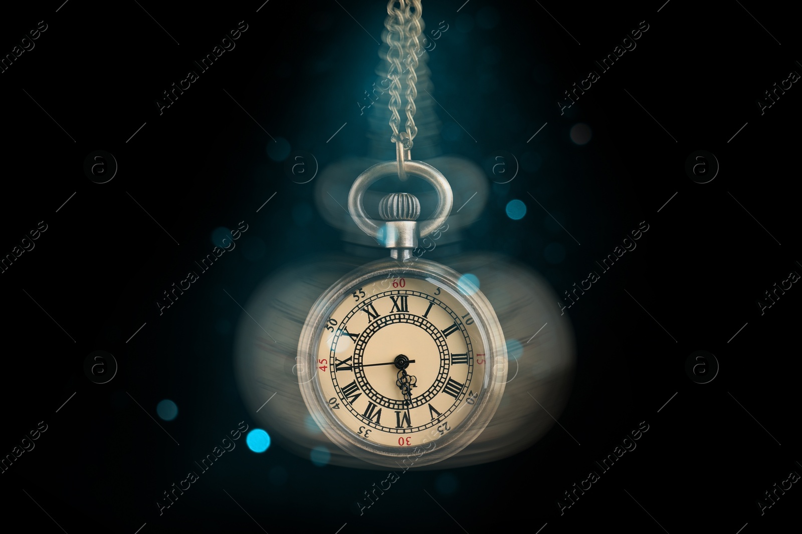 Image of Hypnosis session. Vintage pocket watch swinging on black background, motion blur effect. Magic lights