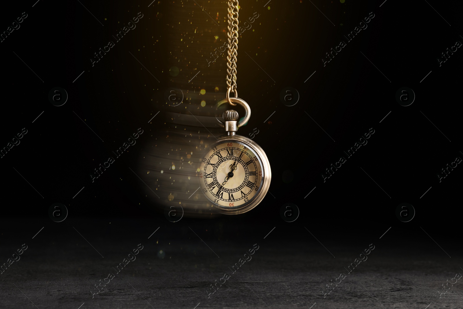 Image of Hypnosis session. Vintage pocket watch swinging on black background, motion blur effect. Magic lights