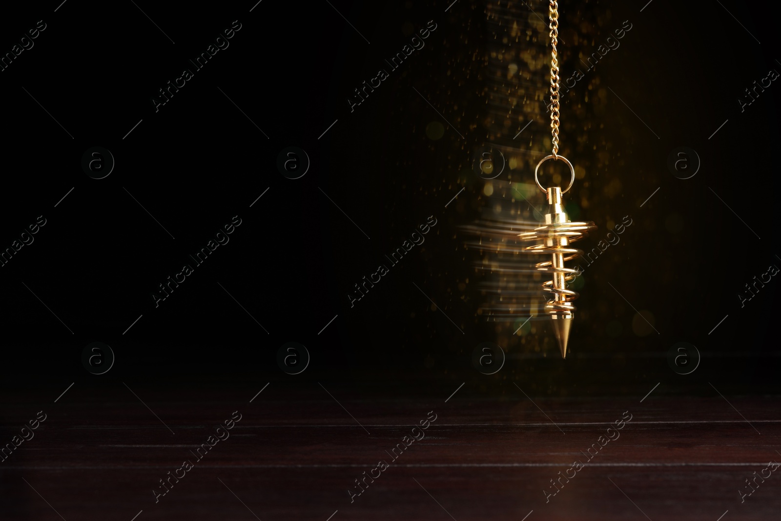 Image of Hypnosis session. Golden pendulum swinging on black background, motion blur effect. Magic lights