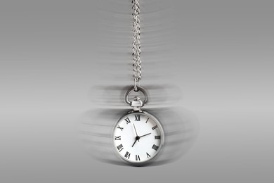 Image of Hypnosis session. Vintage pocket watch swinging on grey background, motion blur effect