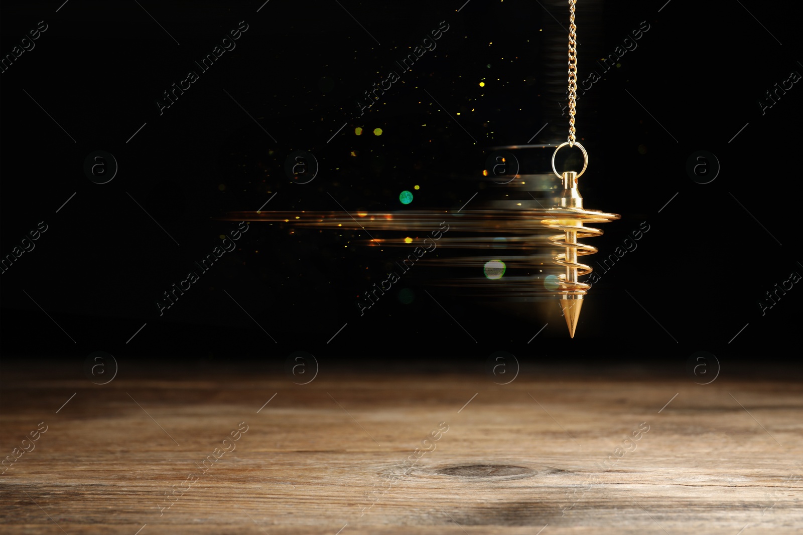 Image of Hypnosis session. Golden pendulum swinging on black background, motion blur effect. Magic lights