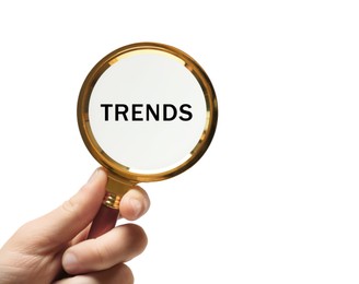 Image of Woman looking at word Trends through magnifying glass on white background, closeup. Concept of searching for new and popular ideas