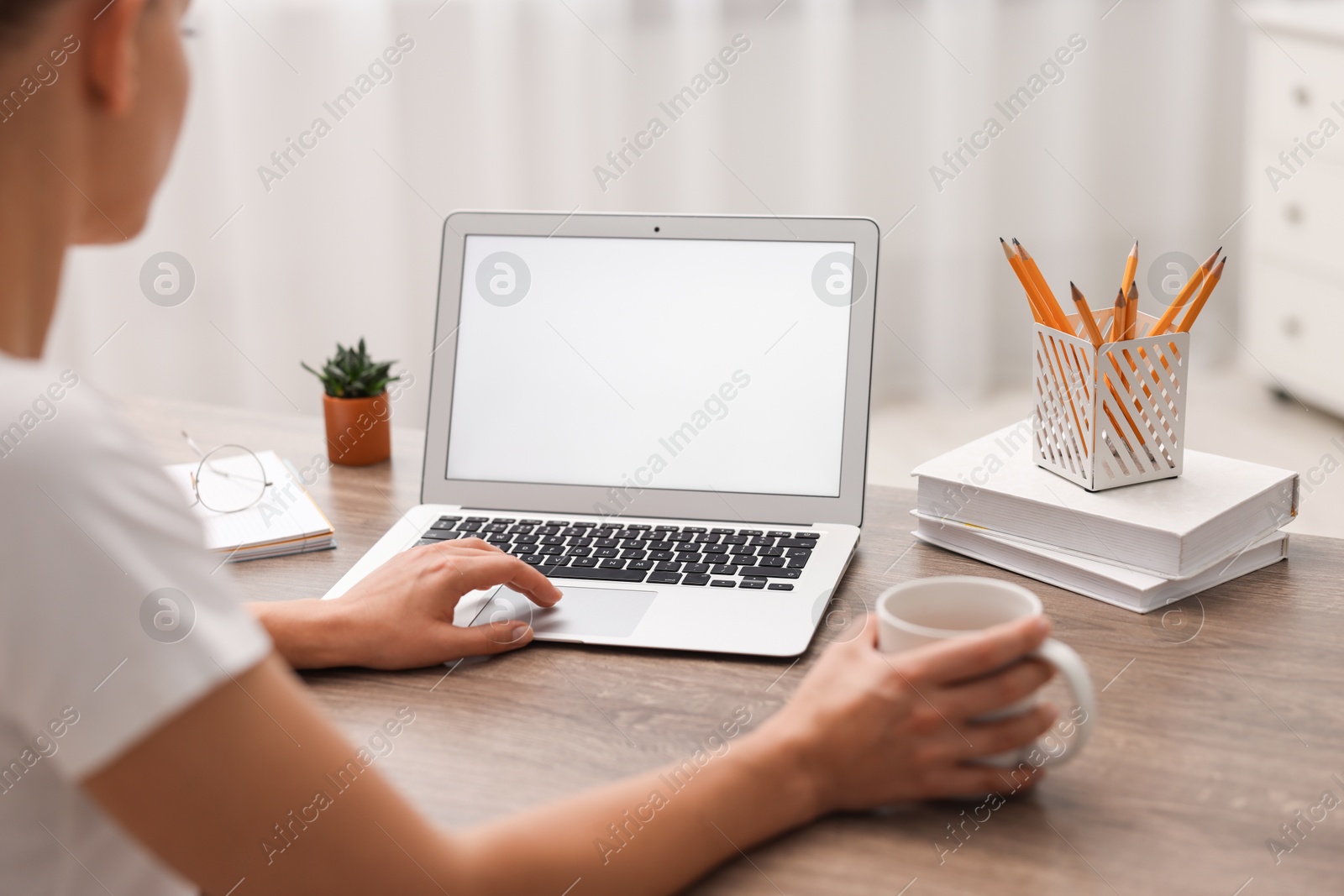 Photo of Woman working with laptop at wooden table in office, closeup. Mockup for design