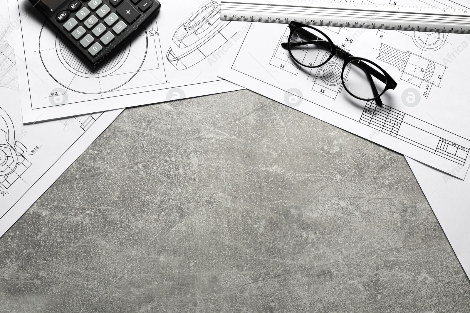 Photo of Different engineering drawings, calculator, ruler and glasses on gray textured table, top view. Space for text