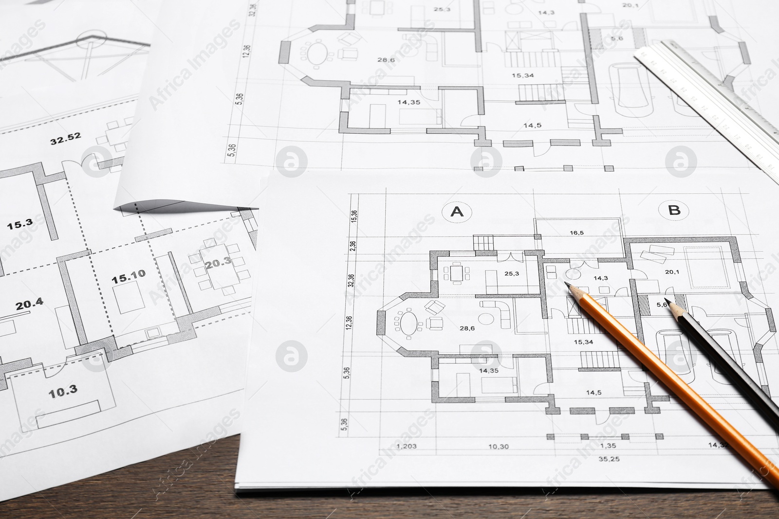 Photo of Different architectural drawings, ruler and pencils on wooden table, closeup