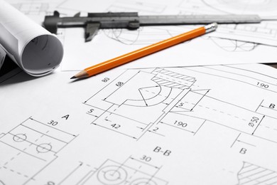 Photo of Different engineering drawings, vernier caliper and pencil on table, closeup