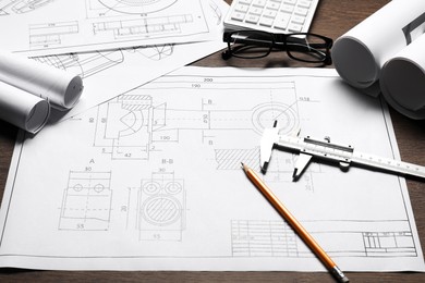 Photo of Different engineering drawings and tools on wooden table, closeup