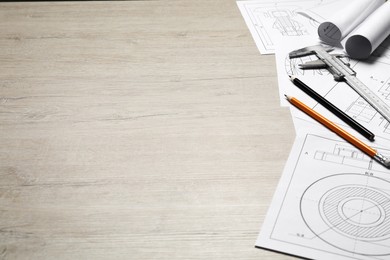 Photo of Different engineering drawings, vernier caliper and pencils on wooden table, space for text