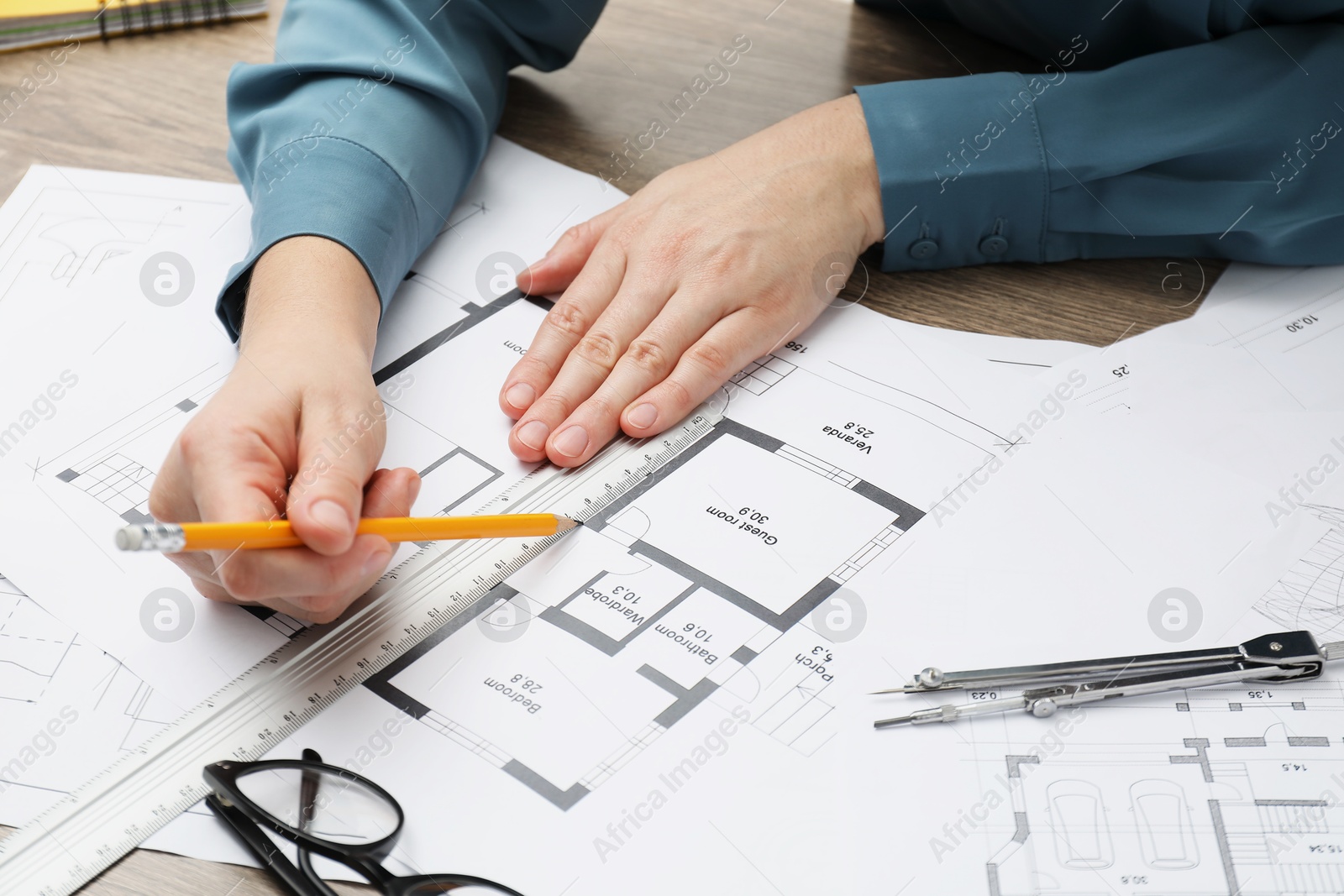 Photo of Architect working with project, closeup. Different technical drawings on wooden table