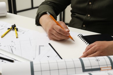 Photo of Architect working with project, closeup. Different technical drawings on white table