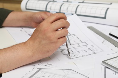 Photo of Architect working with project, closeup. Different technical drawings on table