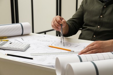 Photo of Engineer working with project, closeup. Different technical drawings on table