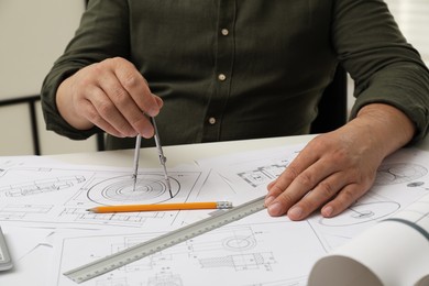 Photo of Engineer working with project, closeup. Different technical drawings on table