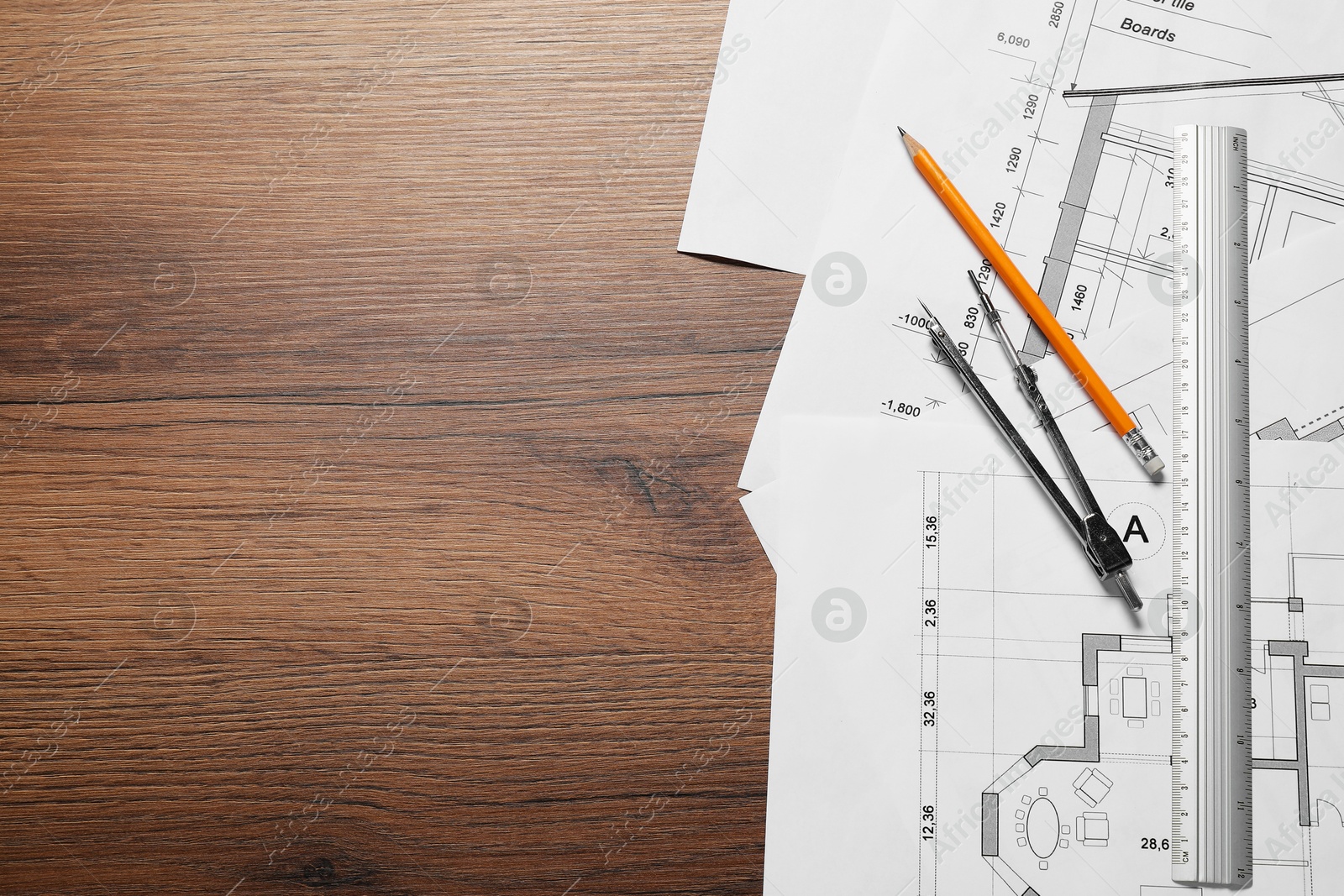 Photo of Different architectural drawings, pencil, ruler and divider on wooden table, flat lay. Space for text