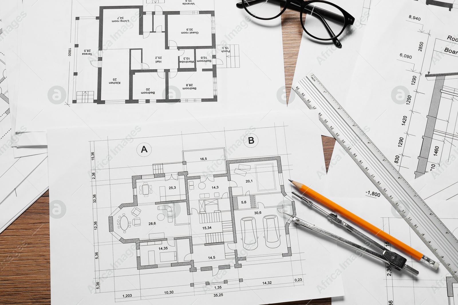 Photo of Different architectural drawings, pencil, ruler, glasses and divider on wooden table, flat lay