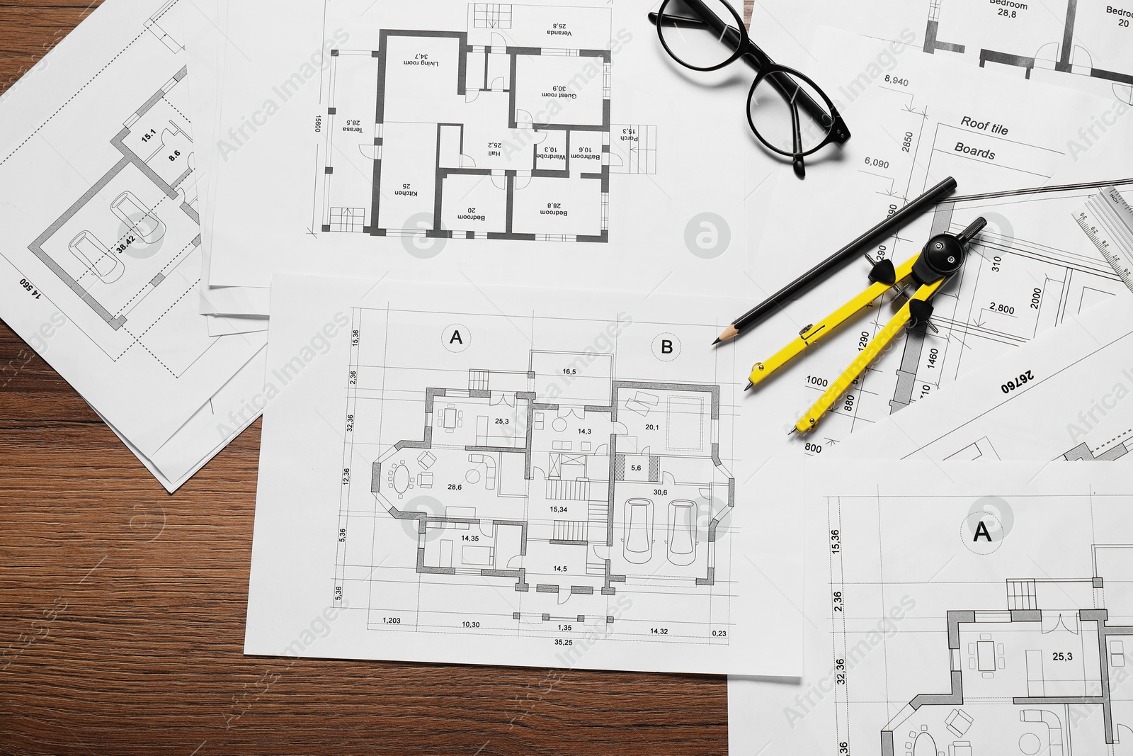 Photo of Different architectural drawings, pencil, glasses and divider on wooden table, flat lay