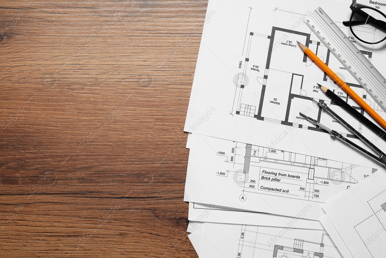 Photo of Different technical drawings, pencils, ruler and divider on wooden table, flat lay. Space for text