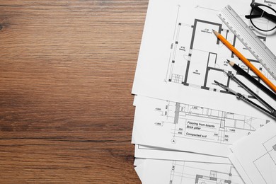 Photo of Different technical drawings, pencils, ruler and divider on wooden table, flat lay. Space for text