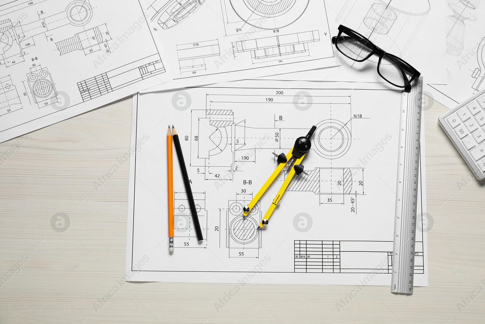 Photo of Different engineering drawings, pencils, glasses and divider on wooden table, flat lay