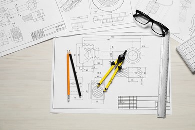 Photo of Different engineering drawings, pencils, glasses and divider on wooden table, flat lay