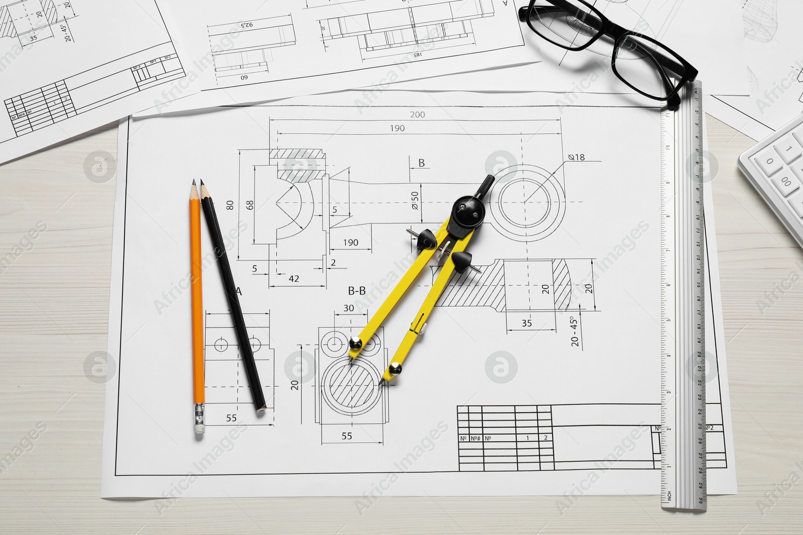 Photo of Different engineering drawings, pencils, glasses and divider on wooden table, flat lay