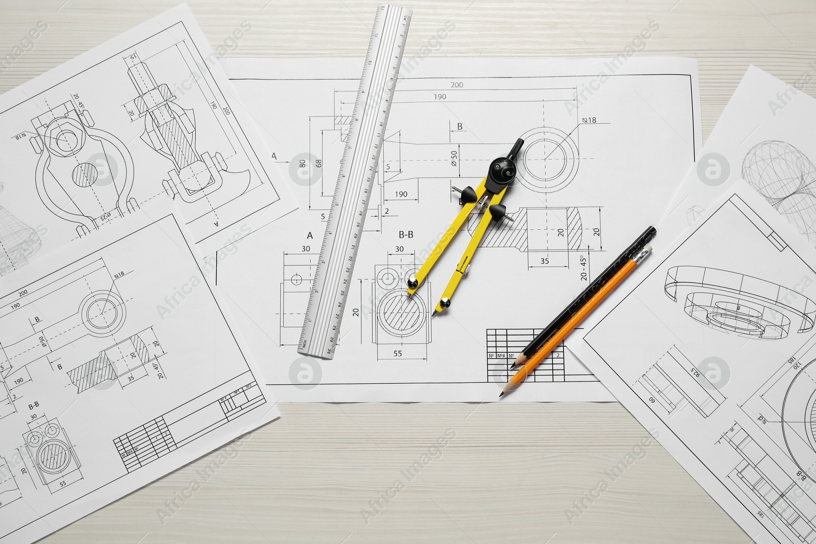 Photo of Different engineering drawings, pencils, ruler and divider on wooden table, flat lay