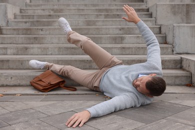 Photo of Injured man on stairs outdoors after fall. Dangerous accident