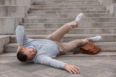 Photo of Injured man on stairs outdoors after fall. Dangerous accident