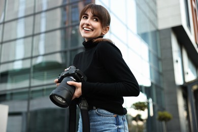 Photo of Professional photographer with digital camera outdoors, low angle view