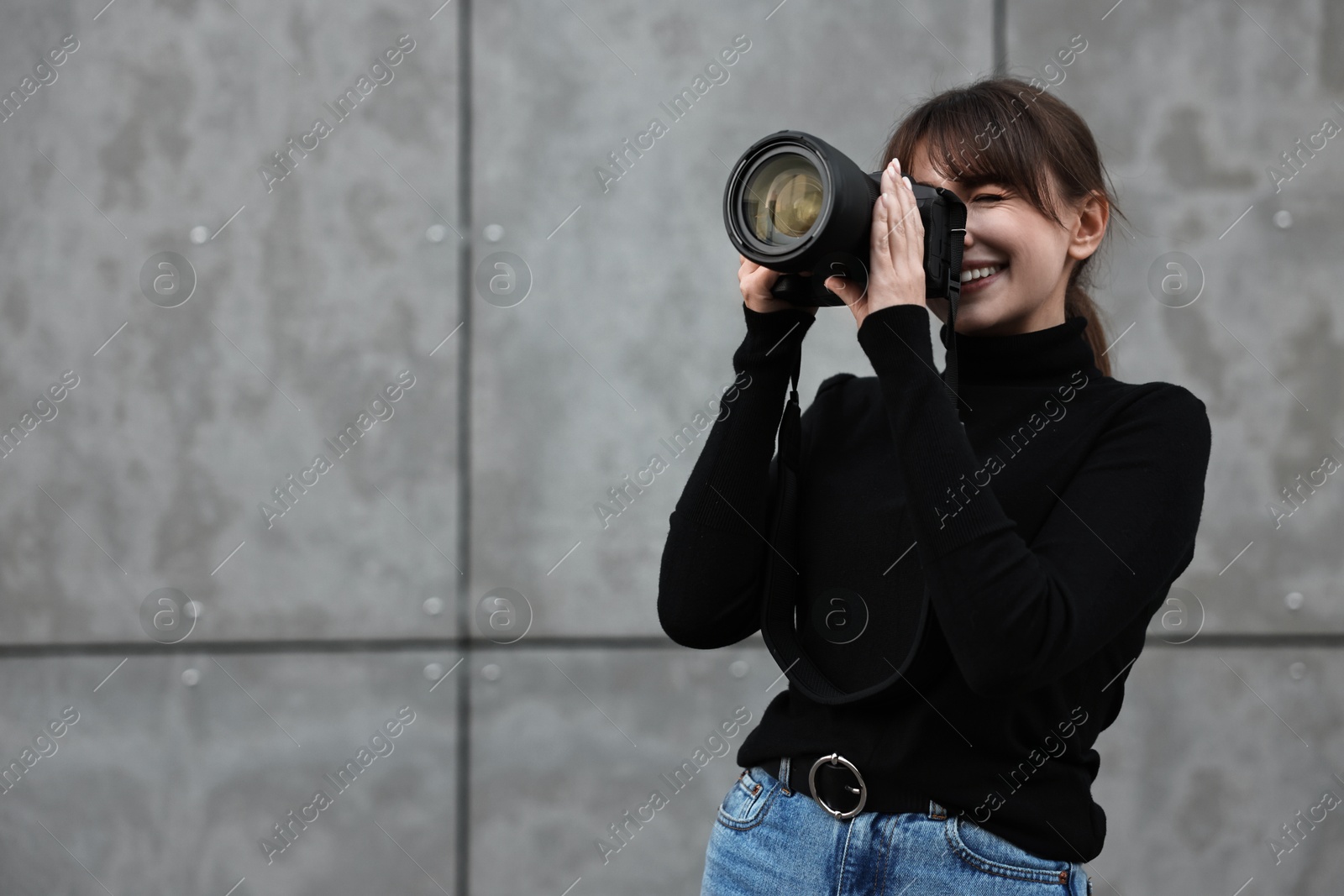 Photo of Professional photographer taking picture with camera near grey wall outdoors. Space for text