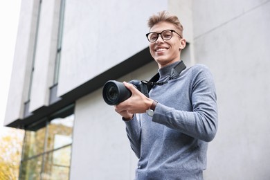 Photo of Professional photographer taking picture with camera outdoors, low angle view