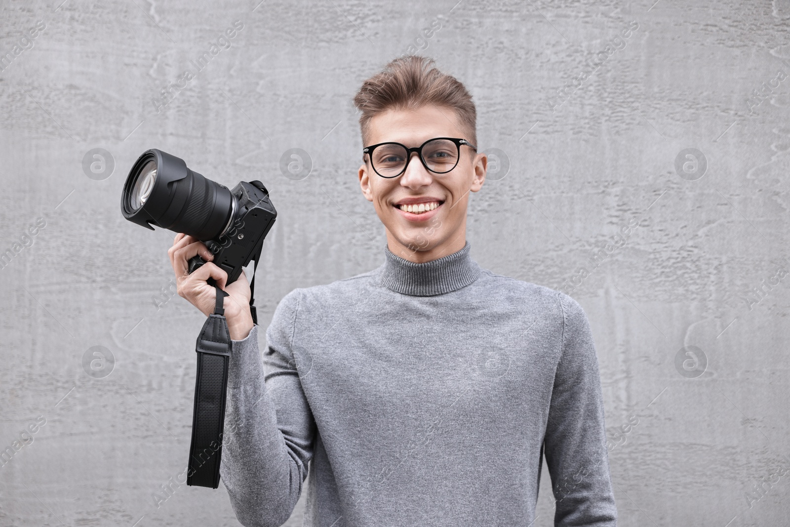 Photo of Professional photographer with camera near grey wall outdoors