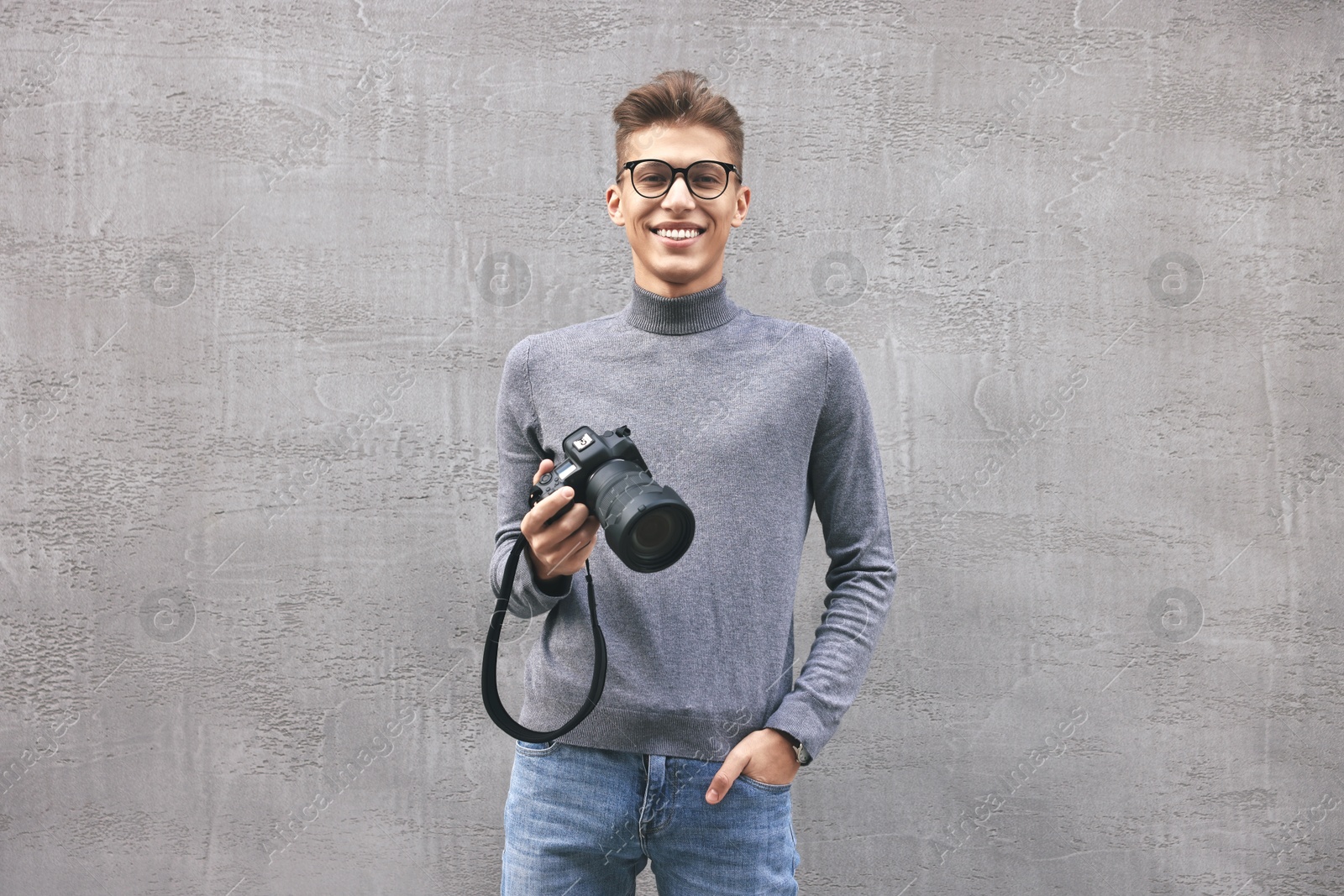 Photo of Professional photographer with camera near grey wall outdoors