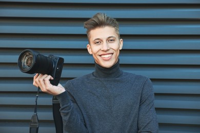 Photo of Professional photographer with camera near grey wall outdoors