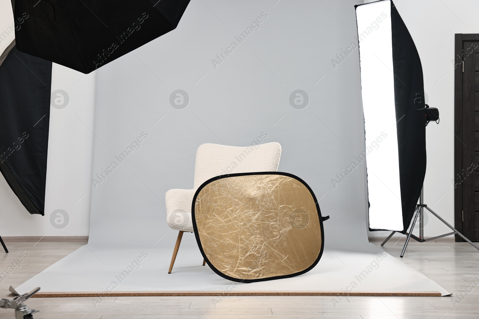 Photo of Professional lighting equipment setup and armchair in modern photo studio