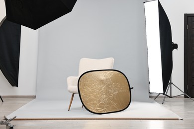 Photo of Professional lighting equipment setup and armchair in modern photo studio