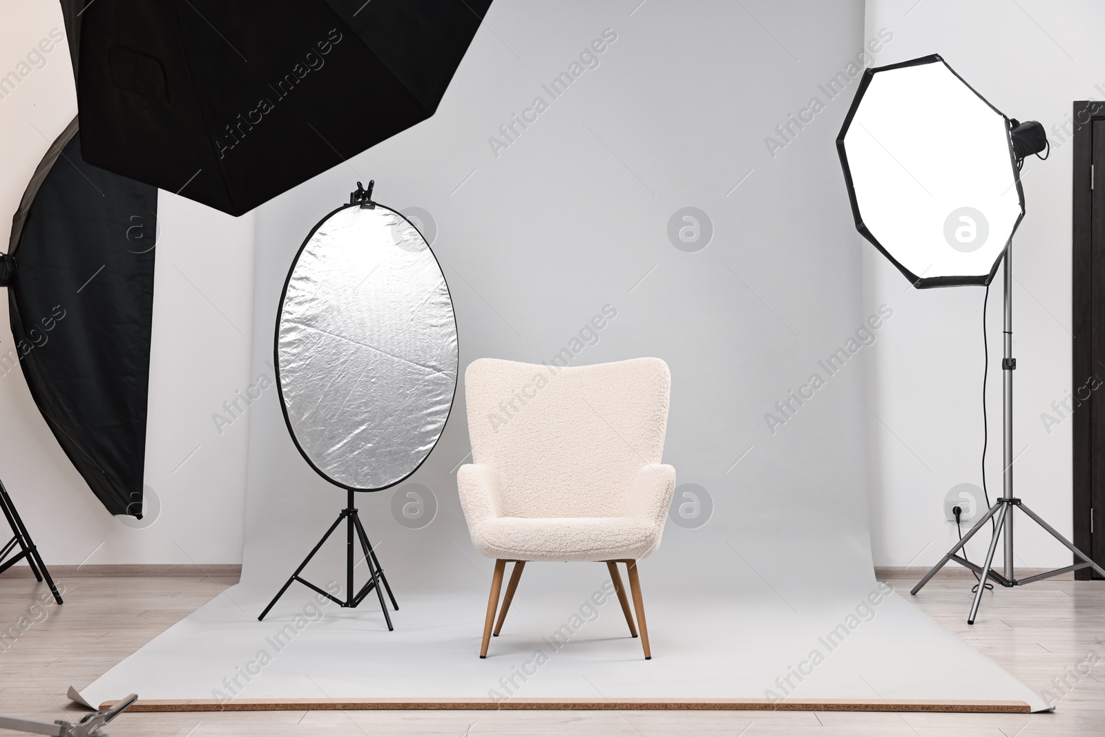 Photo of Professional lighting equipment setup and armchair in modern photo studio