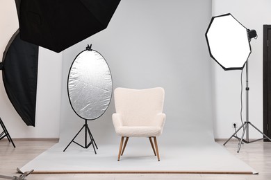 Professional lighting equipment setup and armchair in modern photo studio