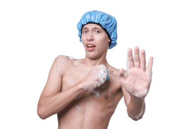 Photo of Man with shower cap and mesh sponge making stop gesture on white background