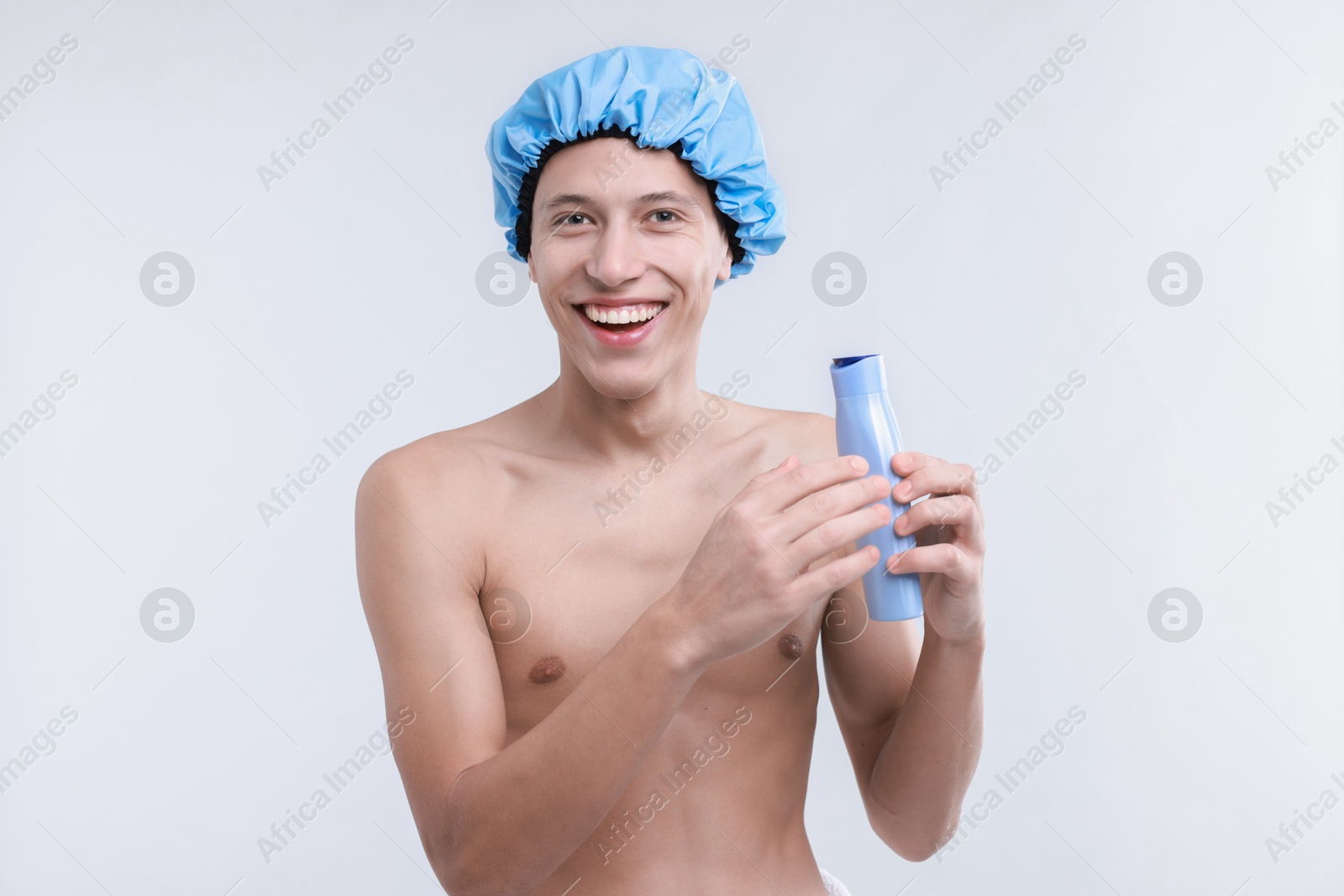 Photo of Man with shower cap and shampoo on light grey background