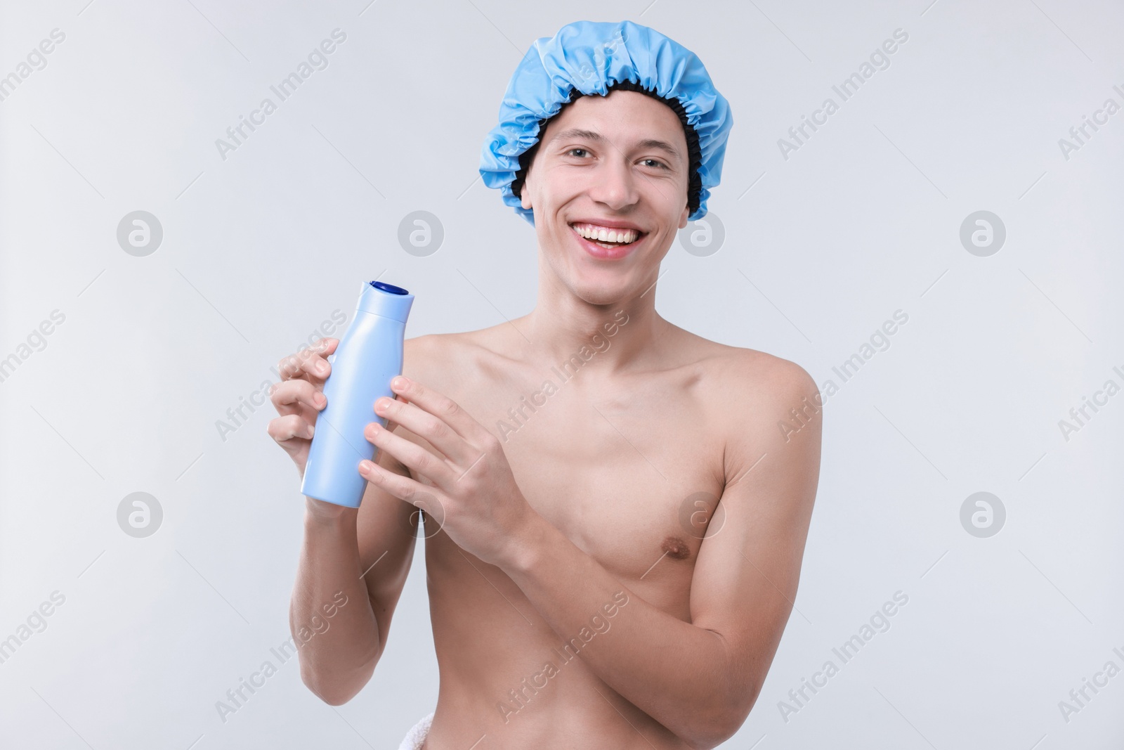 Photo of Man with shower cap and shampoo on light grey background