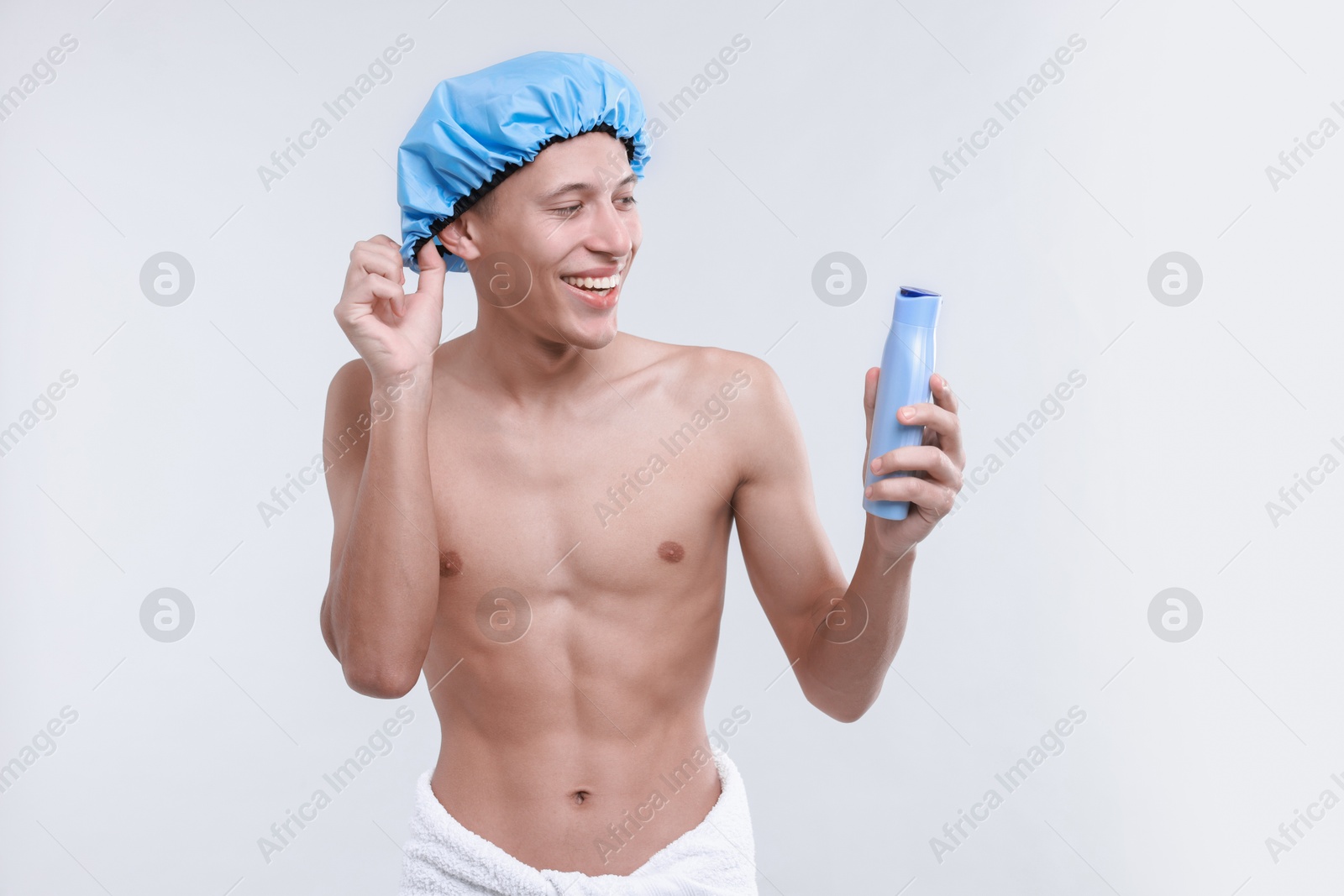 Photo of Man with shower cap and shampoo on light grey background