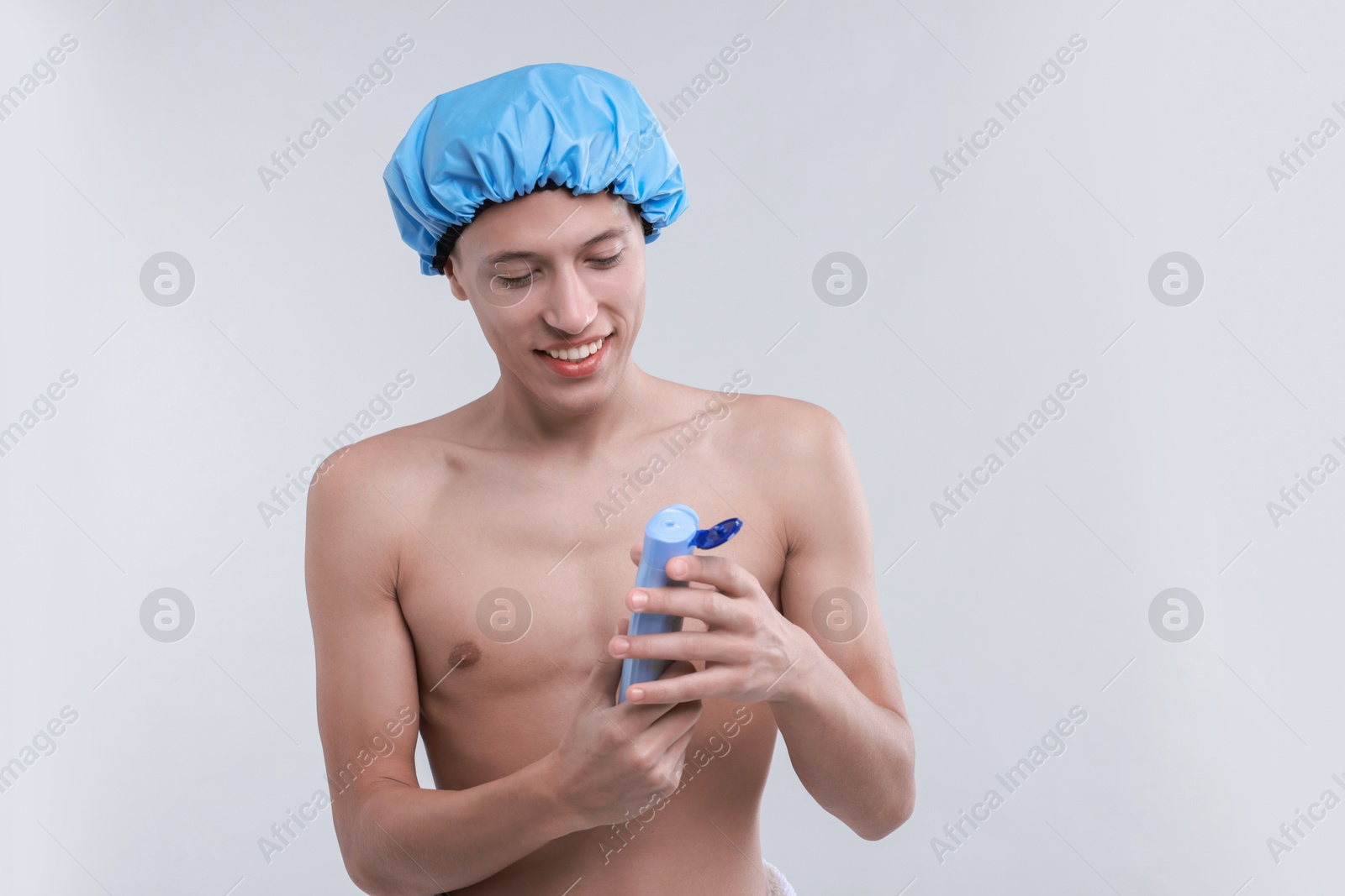 Photo of Man with shower cap and shampoo on light grey background