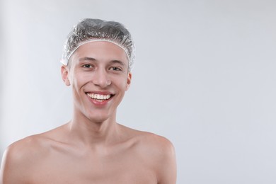 Photo of Man in shower cap on light grey background, space for text