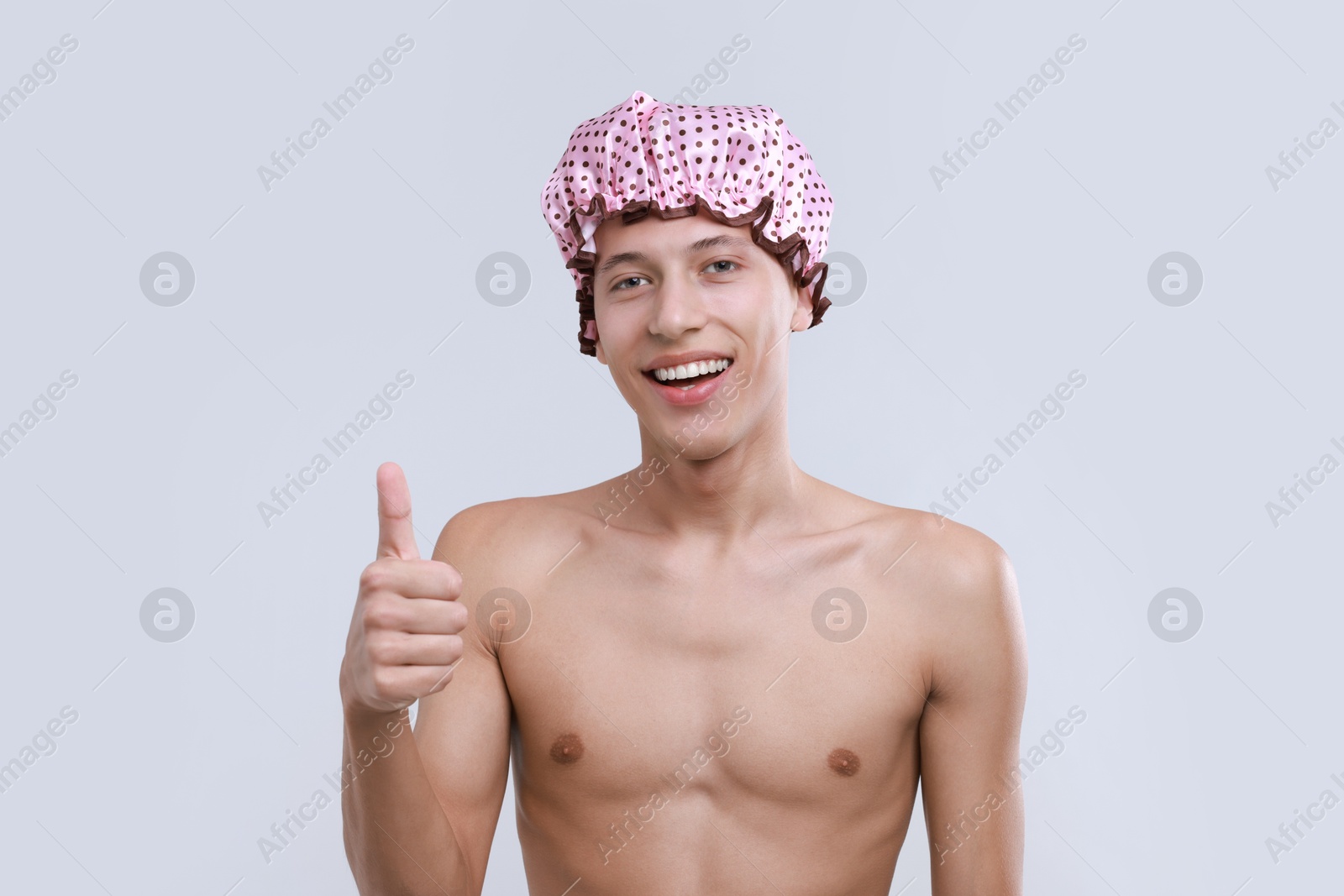 Photo of Man in shower cap showing thumbs up on light grey background