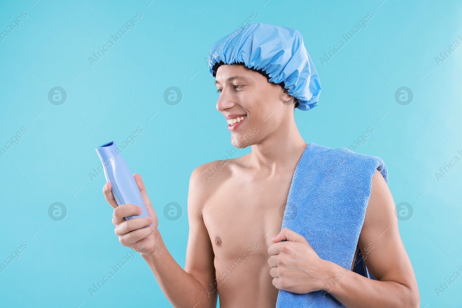 Photo of Man with shower cap, shampoo and towel on light blue background