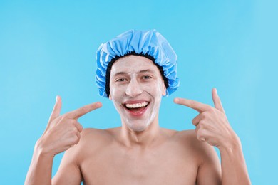 Photo of Man in shower cap with cream on his face against light blue background