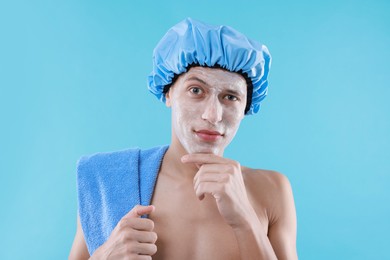 Photo of Man in shower cap with cream on his face against light blue background