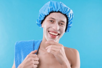 Man in shower cap with cream on his face against light blue background